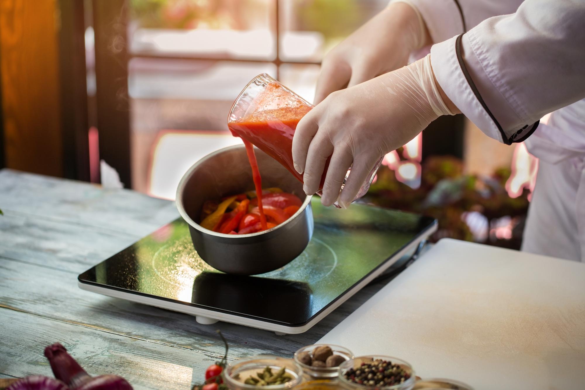 Two chefs demonstrating sauce technique